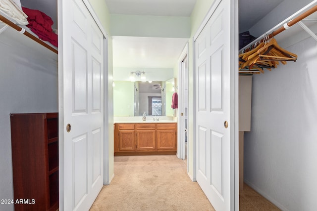 hallway featuring light colored carpet and sink