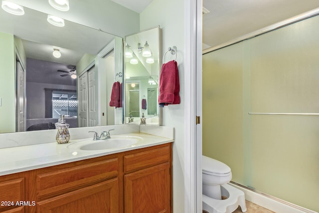 bathroom with toilet, vanity, a shower with door, and ceiling fan