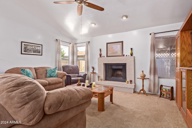 living room with a stone fireplace, vaulted ceiling, light colored carpet, and ceiling fan