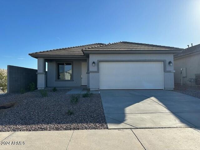 view of front of house featuring a tile roof, stucco siding, driveway, and an attached garage