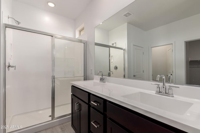 full bath featuring a sink, visible vents, a stall shower, and double vanity