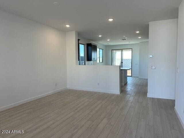 empty room with recessed lighting, light wood-type flooring, and baseboards