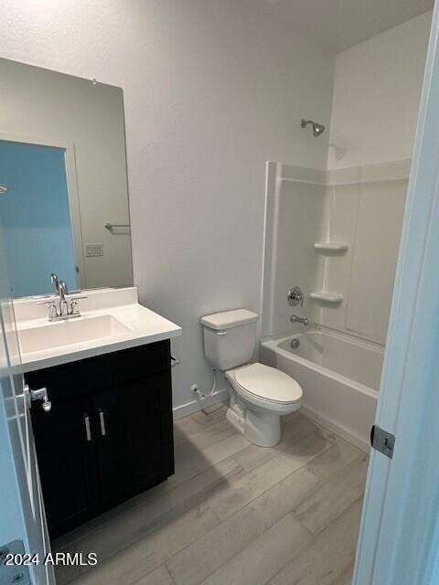 bathroom featuring baseboards, toilet, shower / bath combination, wood finished floors, and vanity