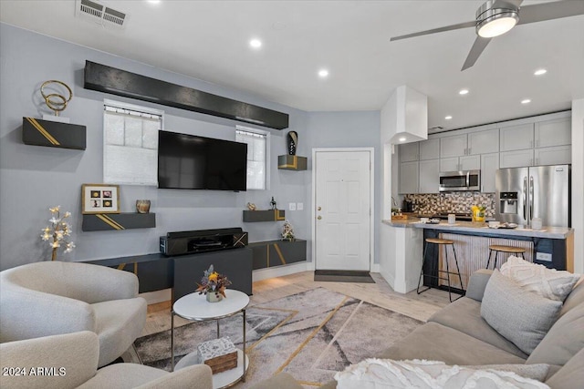 living room featuring visible vents, baseboards, light wood-style flooring, ceiling fan, and recessed lighting