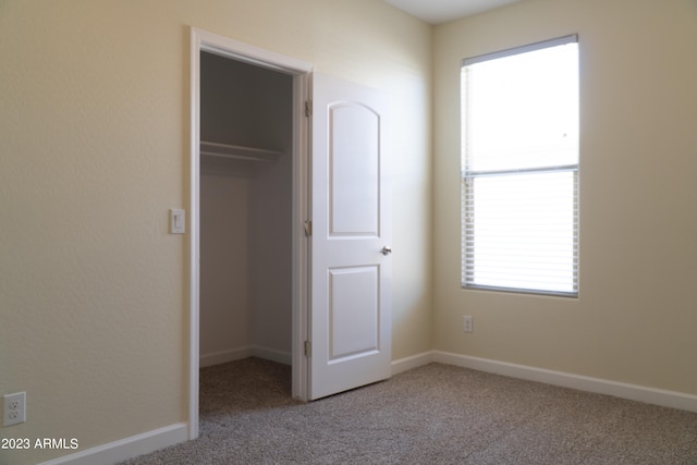 unfurnished bedroom featuring carpet, a closet, and a spacious closet