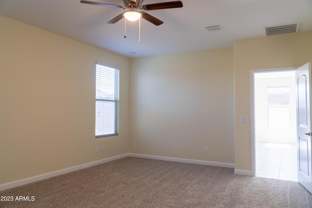 empty room featuring ceiling fan and light colored carpet