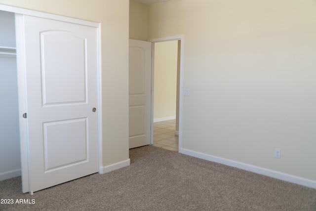 unfurnished bedroom featuring a closet and light carpet