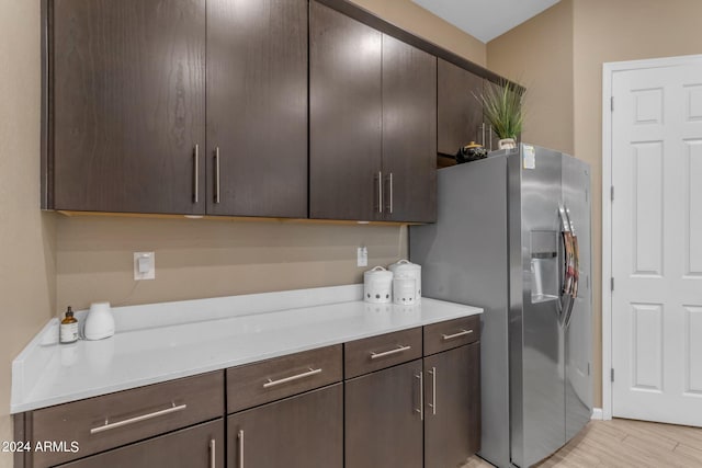 kitchen with dark brown cabinets, light hardwood / wood-style flooring, and stainless steel fridge with ice dispenser