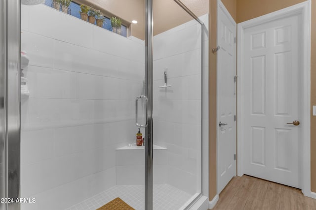 bathroom featuring wood-type flooring and a shower with door