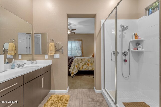 bathroom with hardwood / wood-style floors, ceiling fan, walk in shower, and vanity