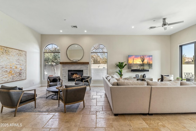 living room with a tile fireplace and ceiling fan