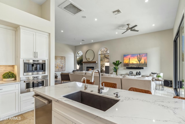 kitchen featuring stainless steel appliances, white cabinetry, sink, and light stone counters