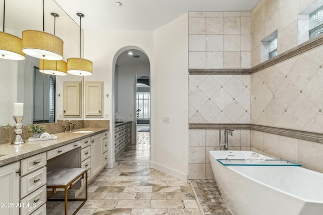 bathroom featuring vanity, tile walls, and a tub