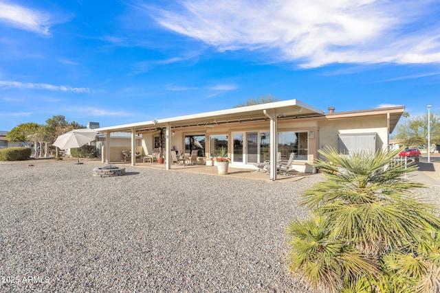 rear view of property with a patio area and an outdoor fire pit