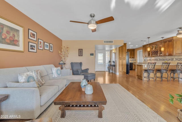 living room featuring ceiling fan and light hardwood / wood-style flooring