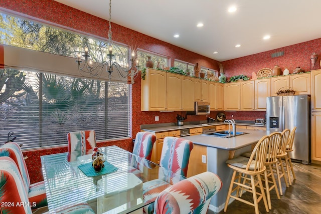 kitchen featuring a center island with sink, hanging light fixtures, sink, appliances with stainless steel finishes, and a notable chandelier