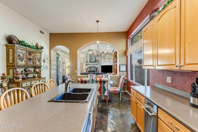 kitchen with tasteful backsplash, light brown cabinetry, sink, and decorative light fixtures