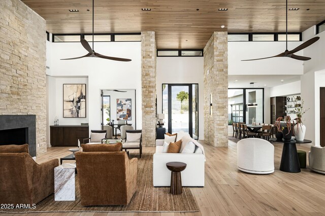 unfurnished living room featuring a towering ceiling, light wood-type flooring, and wooden ceiling