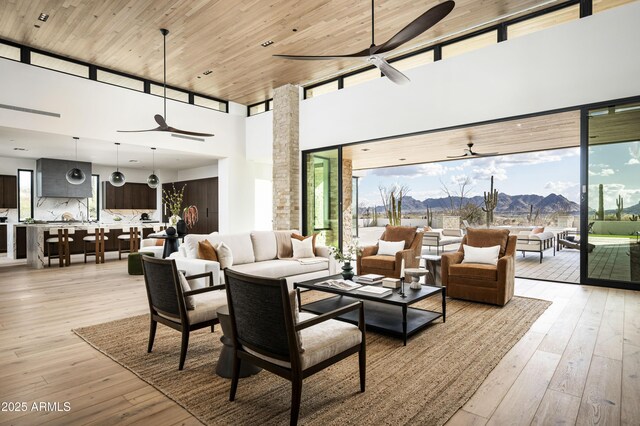 living room featuring a high ceiling, light wood-type flooring, and wood ceiling