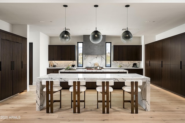 28805 N 114th St, Scottsdale, AZ 85262 - kitchen with decorative backsplash, a breakfast bar, modern cabinets, dark brown cabinets, and light wood-style floors
