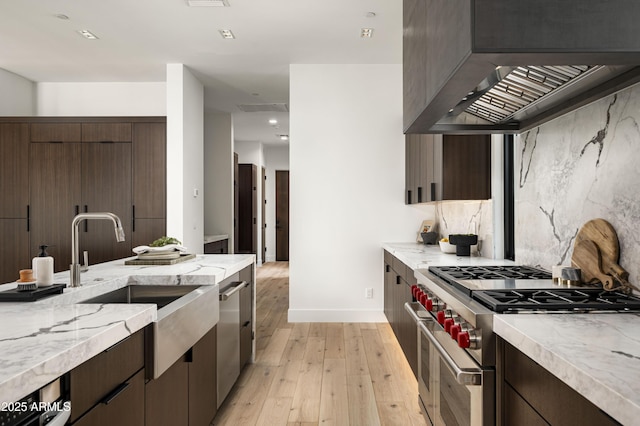 28805 N 114th St, Scottsdale, AZ 85262 - kitchen with decorative backsplash, light wood-style floors, dark brown cabinets, appliances with stainless steel finishes, and wall chimney exhaust hood