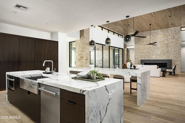 28805 N 114th St, Scottsdale, AZ 85262 - kitchen featuring light wood-style flooring, visible vents, modern cabinets, a stone fireplace, and open floor plan