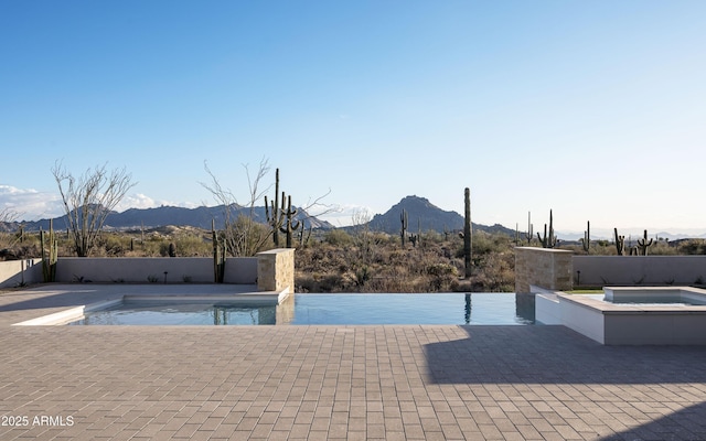 view of pool with a mountain view, a patio, and an in ground hot tub