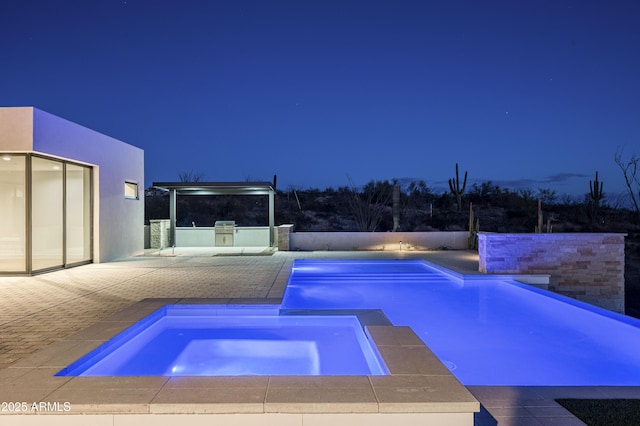 pool at twilight featuring an in ground hot tub and a patio area