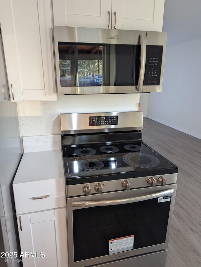 3421 W Montecito Ave, Phoenix, AZ 85017 - kitchen with appliances with stainless steel finishes, white cabinets, light countertops, and wood finished floors
