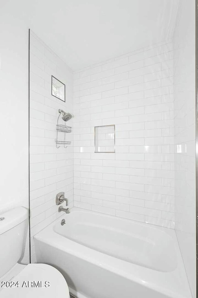 bathroom featuring tiled shower / bath combo and toilet