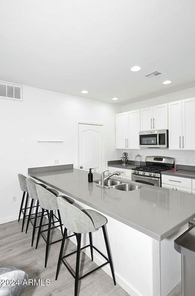 kitchen with white cabinets, appliances with stainless steel finishes, a kitchen bar, and sink