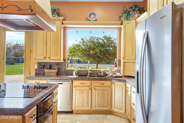 kitchen featuring light brown cabinetry, tasteful backsplash, sink, black appliances, and light hardwood / wood-style flooring