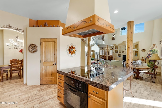 kitchen with black appliances, a breakfast bar, light wood-type flooring, and island exhaust hood