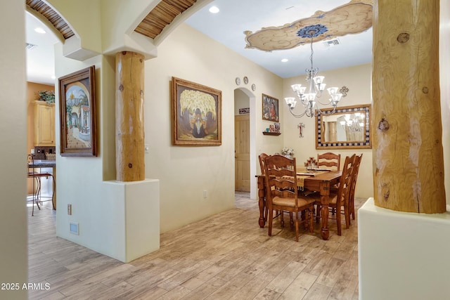 dining space with light hardwood / wood-style floors and an inviting chandelier