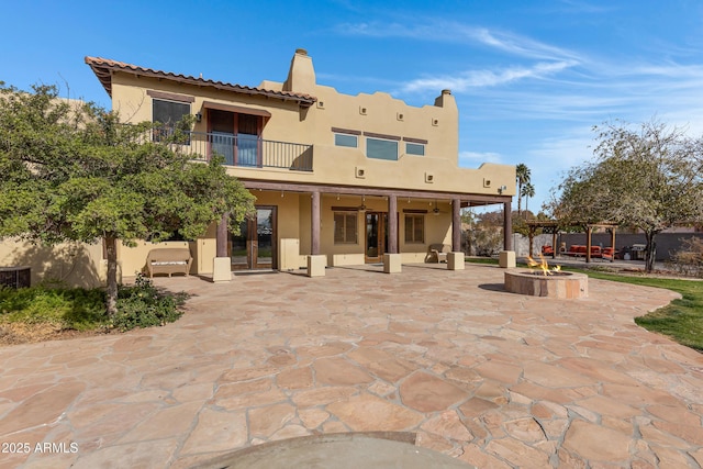 back of property featuring a patio, a balcony, an outdoor fire pit, and ceiling fan