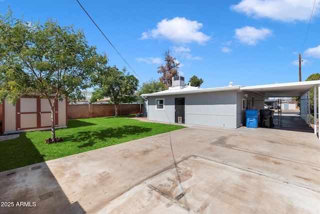 back of house with an attached carport, an outbuilding, driveway, a storage shed, and a lawn