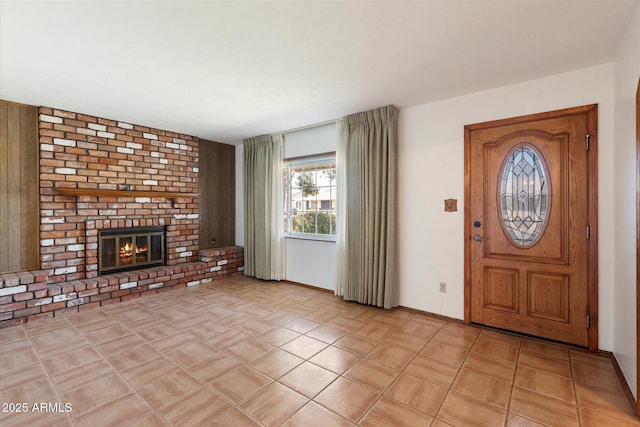 entryway featuring baseboards, light tile patterned flooring, and a fireplace