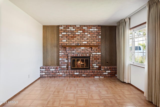 unfurnished living room with a brick fireplace and baseboards