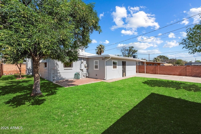 rear view of house featuring a patio, a lawn, and fence