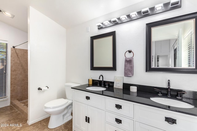 bathroom with toilet, tile patterned flooring, vanity, and a tile shower