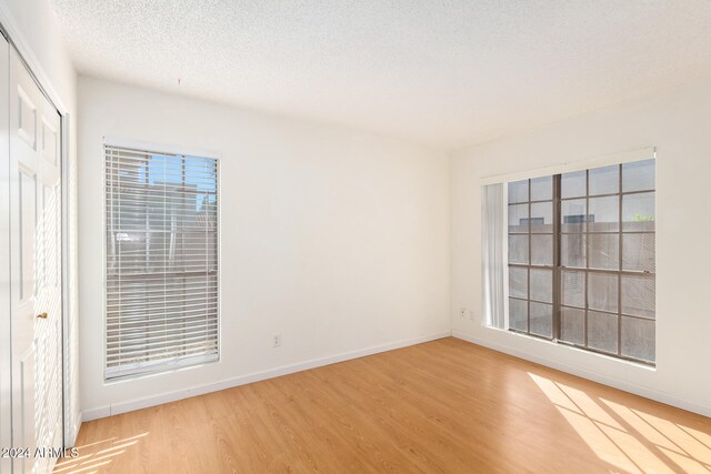 spare room featuring light hardwood / wood-style flooring and a textured ceiling