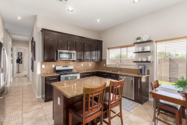6719 N 15th Ave, Phoenix, AZ 85015 - kitchen featuring stainless steel appliances, a sink, dark brown cabinetry, backsplash, and light stone countertops