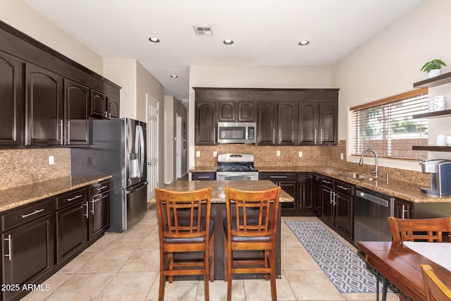 6719 N 15th Ave, Phoenix, AZ 85015 - kitchen featuring appliances with stainless steel finishes, a sink, light stone countertops, a kitchen island, and decorative backsplash