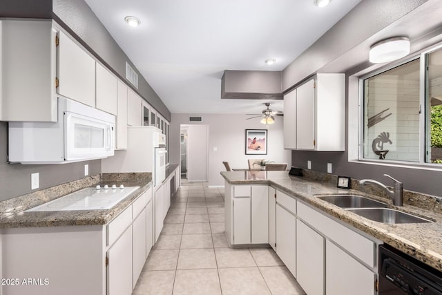 kitchen with white appliances, a sink, a peninsula, white cabinets, and ceiling fan