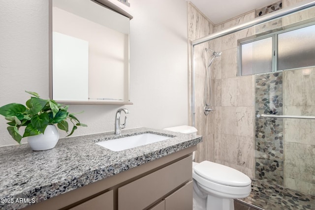 bathroom with a tile shower, toilet, and vanity