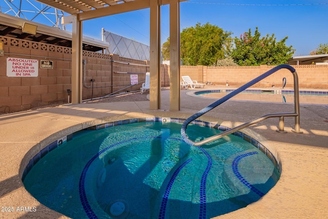 community pool featuring a hot tub, a fenced backyard, and a patio