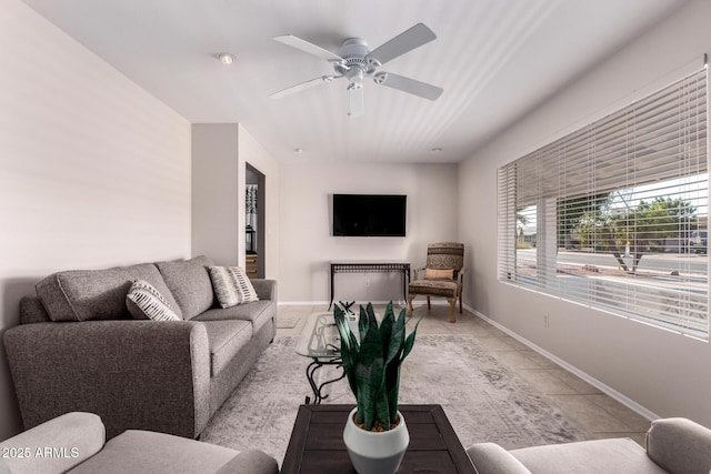 living room with light tile patterned floors, a ceiling fan, and baseboards