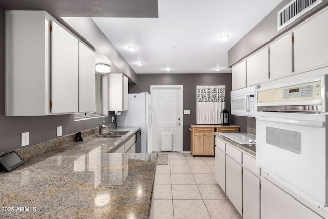 kitchen featuring white appliances, a sink, white cabinetry, light stone countertops, and light tile patterned floors