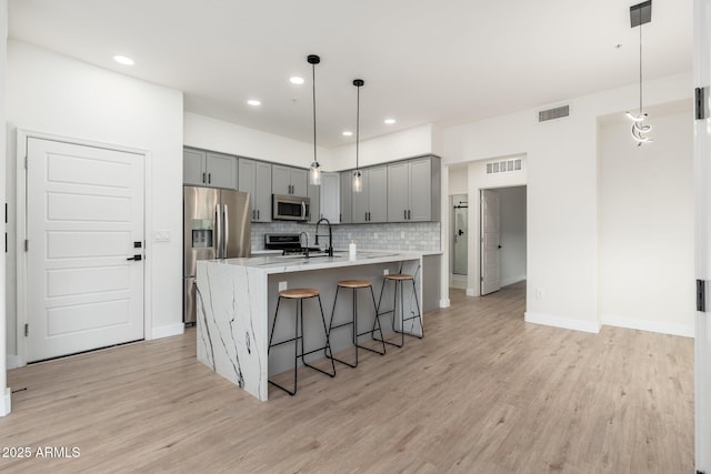 kitchen with stainless steel appliances, gray cabinets, pendant lighting, and decorative backsplash