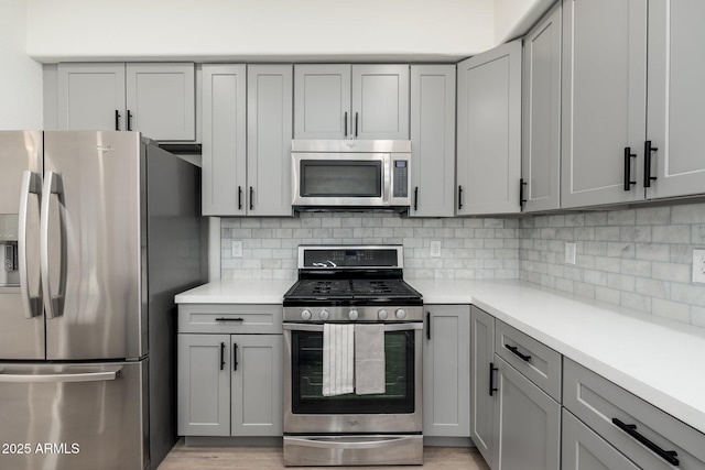 kitchen with gray cabinetry, decorative backsplash, and stainless steel appliances